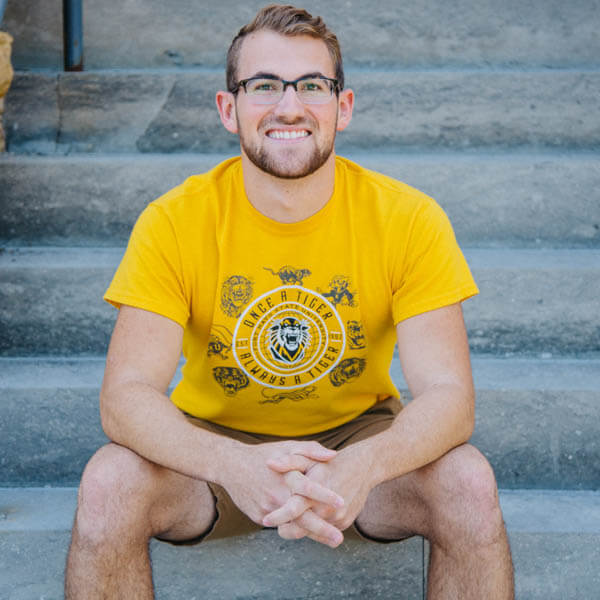 Student sitting in front of Picken Hall