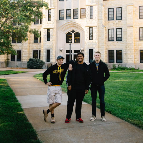 three students standing in front of McCartenery Hall