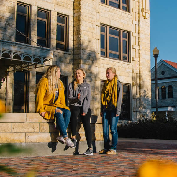 three students chatting in front of Sheridan Hall