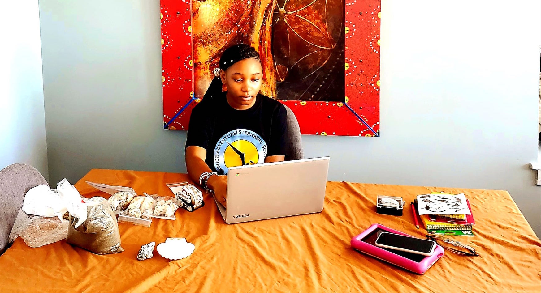 Surrey Jones, a middle school camper from Chicago, works at her family’s dining room table, surrounded by materials she received in her camp kit box for the Ancient Seas camp.