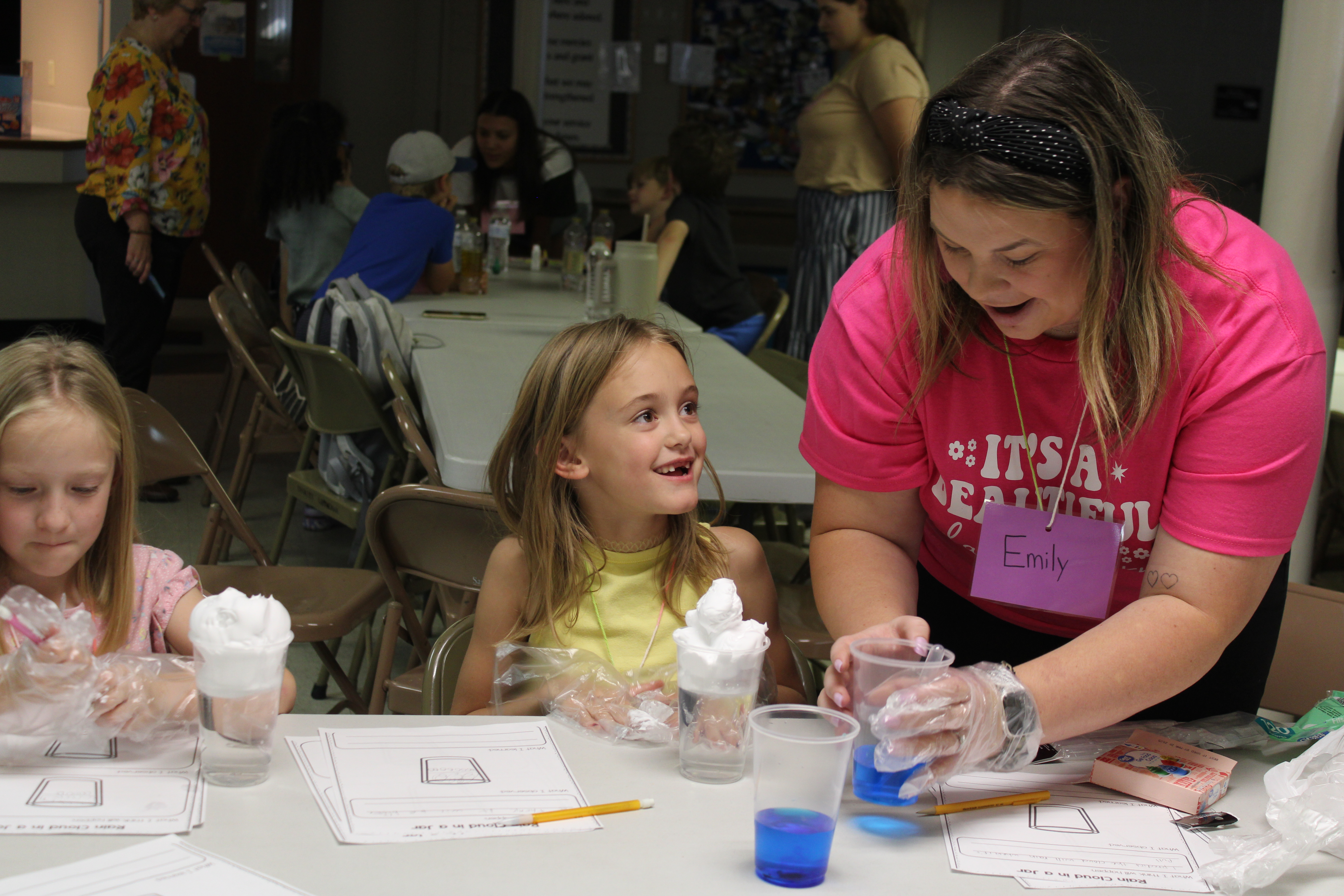 During an after-school science program at Trinity Lutheran Church, Emily Ritchey, a senior elementary education major from St. George, demonstrates how to build a rain cloud in a jar.