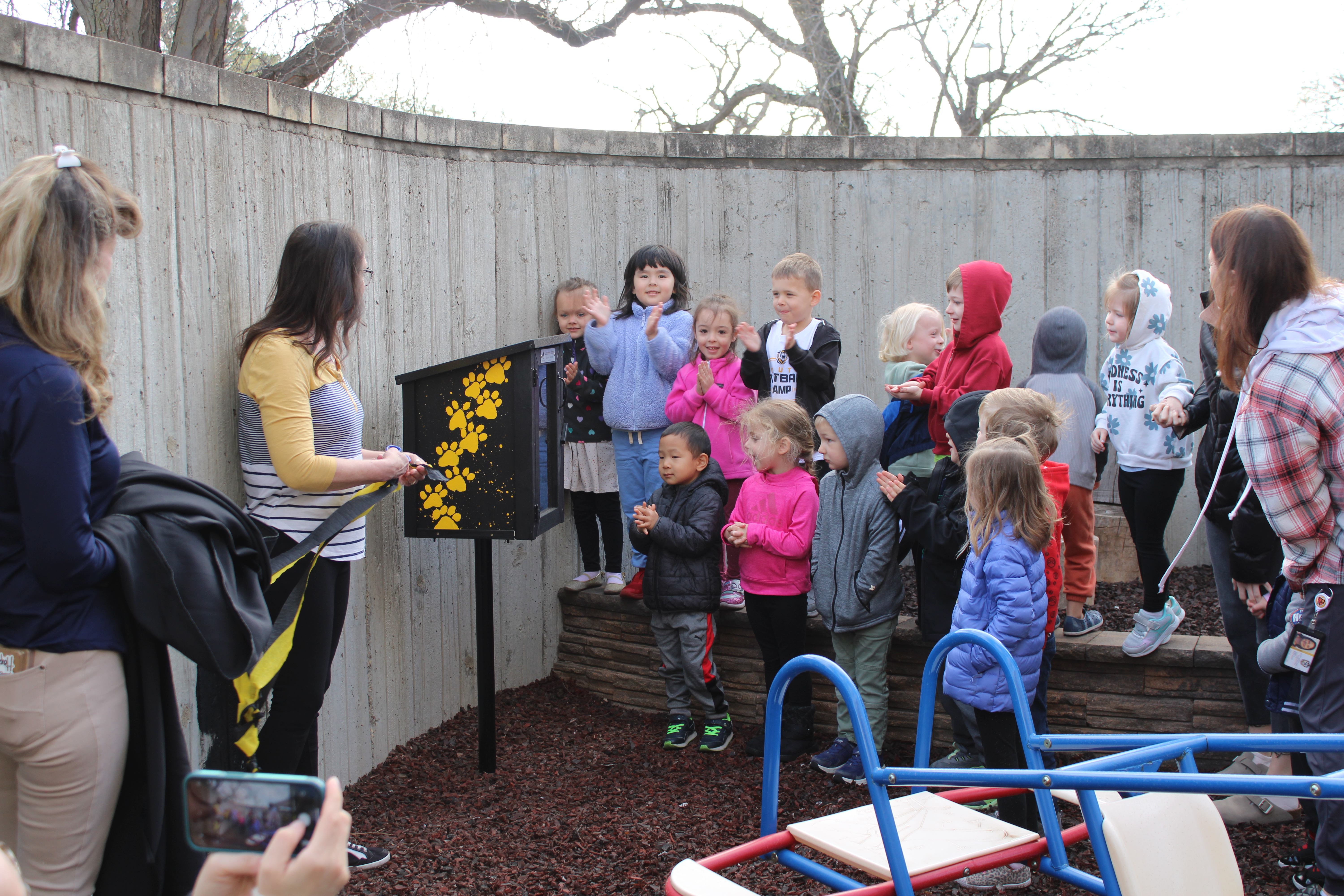 Tiger Tots preschoolers clap as their new outdoor library is revealed