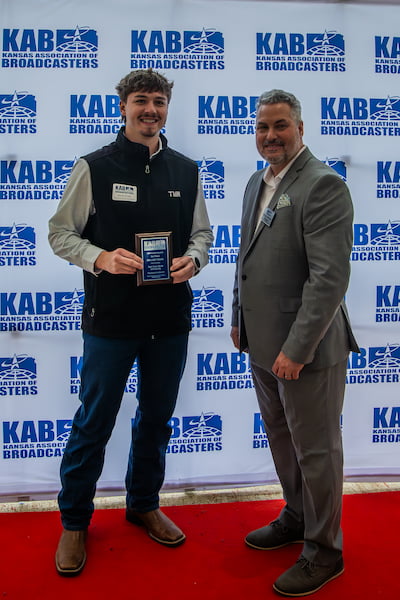 Kyson Evans accepts the first-place plaque for documentary from Gregg Hibbeler, president of the Kansas Association of Broadcasters, during the April 9 awards ceremony in Kansas City, Missouri.